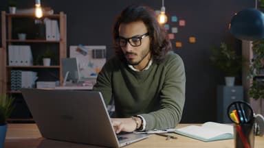 Developer working on a laptop in a dimly lit office