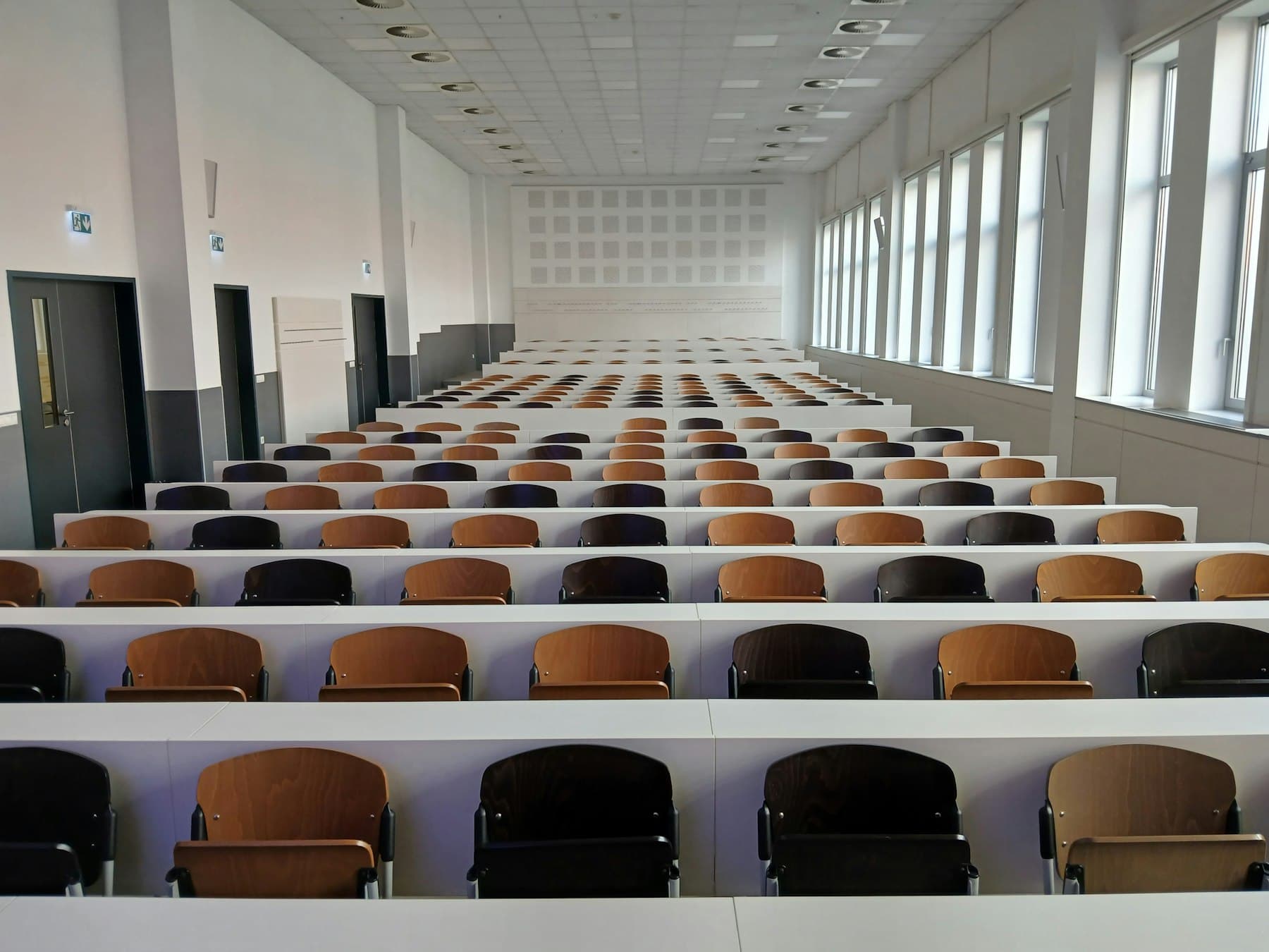 Lecture hall with rows of seats and tall windows